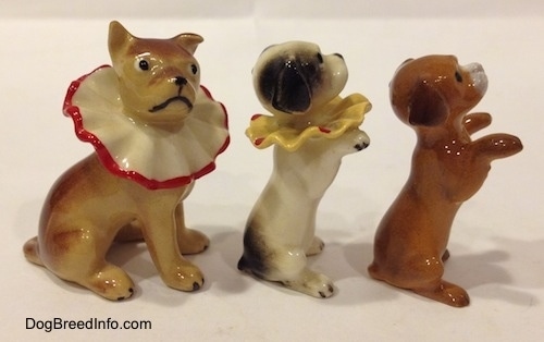 The right side of three circus dog figurines. Two of the figurines are wearing neck ruffles.