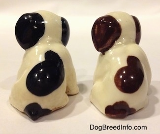 The back of two dog figurines in a sitting position that are different color variations. The figurines have ears that are a solid color.