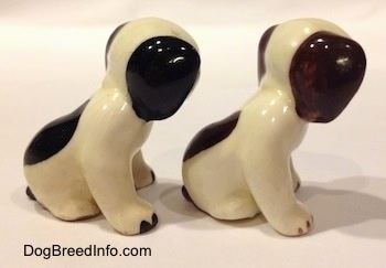 The right side of two dog figurines that are in a sitting positions and are different color variations. The figurines have color tipped nails.