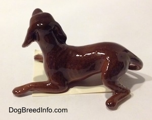 The left side of a brown figurine of a playful dog. The figurine is very glossy.