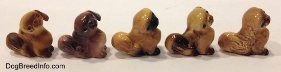 The right side of five different color variations of a Pekingese puppy seated figurine.