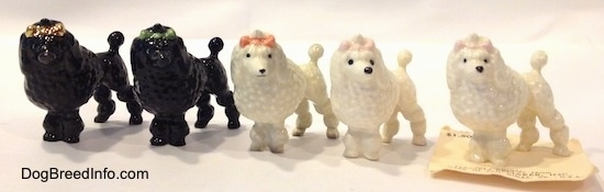 A line-up of five different color variations of a Poodle with a bow in its hair figurine.