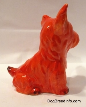 The right side of an orange miniature Schnauzer figurine sitting. The figurine has fine hair details.