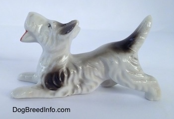 The left side of a white with black bone china Schnauzer figurine. The figurine has fine hair details along its body and legs.