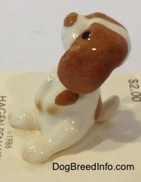 The left side of a white and brown Miniature Curbstone Setter puppy figurine that is in a begging pose.