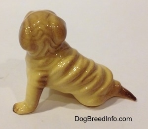 The left side of a chinese Shar-Pei figurine sitting. The figurine has medium length legs.