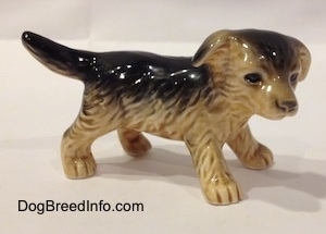 The right side of a black with tan figurine of a German Shepherd puppy. The figurine has fine hair details.