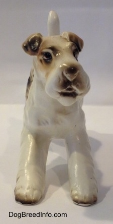 A ceramic white with tan and black Wire Fox Terrier figurine. The figurines face lacks detail.