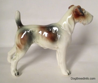 The right side of a figurine of a white with brown and black Wire Fox Terrier. The figurine has a tail in the air.