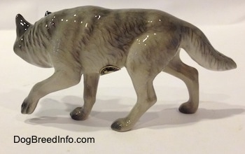 The left side of a stalking figurine of a gray Wolf. The figurine has a long tail.
