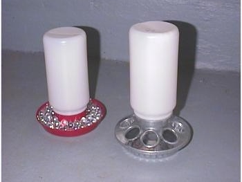 A water feeder with clear marbles in it and a food feeder.