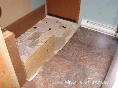 The play area and potty are of a whelping box separated by a wood divider.