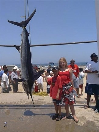 A fish with a long nose and a big fin(Striped Marlin) is hanging upside down from a line.