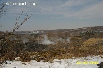 A steaming wasteland with a little bit of snow in the foreground