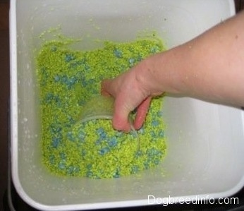 yellow and blue gravel is being scooped out of a white bucket