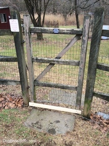A wooden split rail gate with a metal wire back to the fence.