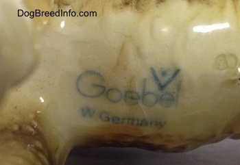 Close up - The logo of Goebel that is on the underside of a black and tan with white Vintage Goebel Airedale Terrier porcelain dog figurine.
