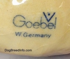 Close up - The logo of - Goerbel W. Germany - is on the underside of a black and tan with white second vintage Goebel Airedale Terrier porcelain dog figurine. You can see cracks in the outside coating around the logo.