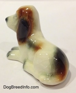 The back left side of a white with black and red Basset Hound figurine. The figurine ears are attached to it.
