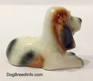 The right side of a white with black and red Basset Hound figurine. The figurine has great wrinkly face detail.