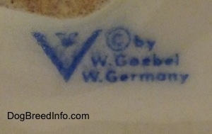 Close up - The underside of a white with black and red Basset Hound figurine that has the logo of W. Goerbel on it.