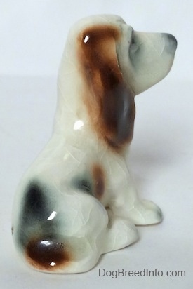 The back right side of a white with black and red ceramic Basset Hound figurine. The ears are not very detailed.