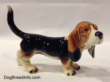The right side of a black with white and brown Basset Hound figurine. The face of the figurine has fine details.