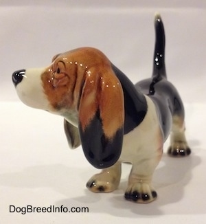 The front left side of a black with white and brown Basset Hound figurine. The ears on the figurine are well defined.