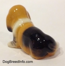 The back left side of a tan and black with white ceramic Basset Hound figurine. The figurine has not tail.
