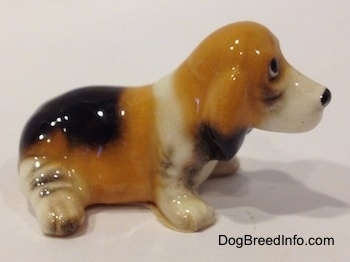 The right side of a tan and black with white ceramic Basset Hound figurine. The paws of the figurine lack fine detail.