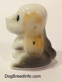 The left side of a white with tan and black bone china Basset Hound puppy figurine. The figurine has a short tail.