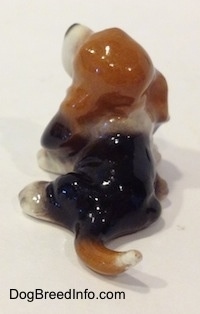 The back of a black and brown with white ceramic Basset Hound figurine that is looking up.