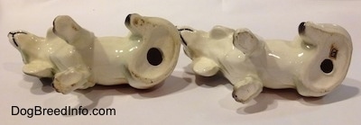 The underside of two brown and white with black ceramic Basset Hound figurines.