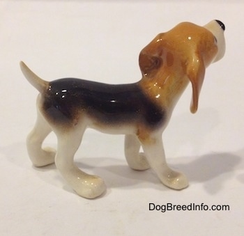 The right side of a black and white with tan miniature Beagle figurine. The ears of the figurine are not attached to the body.