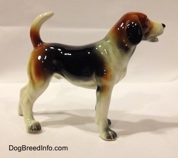 The right side of a black, brown and white Beagle figurine. The tail of the figurine is arched up.