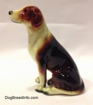 The left side of a black, brown and white porcelain Beagle figurine. The ears of the figurine are indistinguishable from the body.