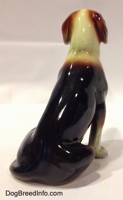 The back right side of a black, brown and white porcelain Beagle figurine. The figurine is very glossy.