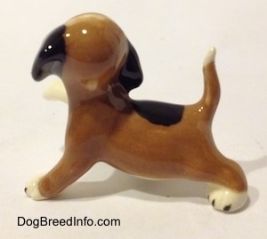 The right side of a brown, black and white miniature Beagle figurine in a standing pose with its paw up. The figurine has a large black spot on it back.