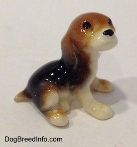 The right side of a black, brown and white Beagle puppy figurine.