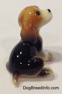 The back right side of a black, brown and white Beagle puppy figurine. Its hard to tell the difference between the ears of the figurine from the body.