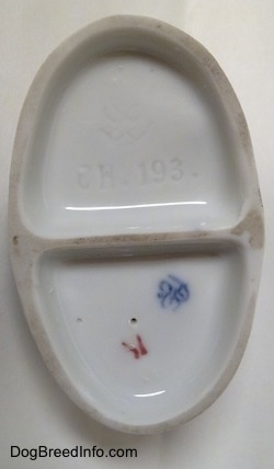 The underside of a figurine. There is a logo and numbers on it.
