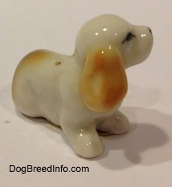 The right side of a bone china white with tan and black tiny Beagle puppy figurine. The figurine has detailed ears.