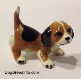The right side of a brown, black and white miniature Beagle in a crouching pose. The face details of the figurine are cartoony.