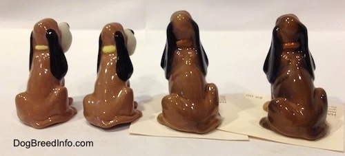 The back side of a line up of four Hagen-Renaker Bloodhound figurines. The figurines are very glossy.