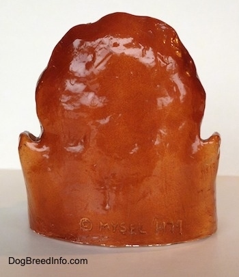 The back of a highly detailed figurine of the head of a Bloodhound dog. It has a copyright on the back of its head.