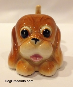 A tan Cartoon style Bloodhound puppy. The nose of the figurine is off by a small portion.