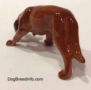 The back left side of a Hagen-Renaker miniature red variation of a Bloodhound figurine.