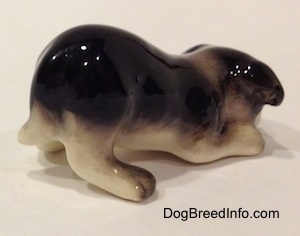 The back right side of a Hagen-Renaker miniature black with white Border Collie puppy figurine. The appendages of the figurine are not very detailed.
