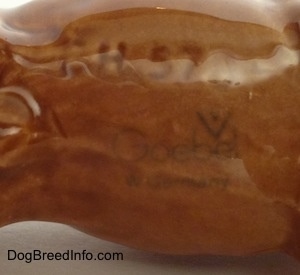 Close up - The underside of a porcelain brown Boxer dog figurine. On the underside is the Goebel W. Germany logo.