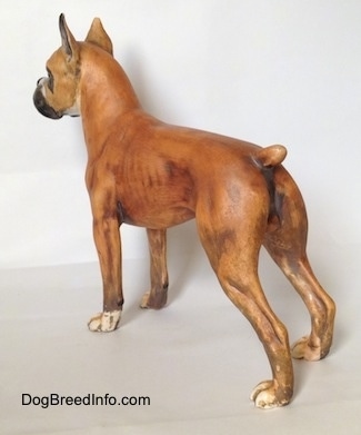 The back left side of a brown with black and white Boxer figurine with a matte finish. The feet of the figurine are white.